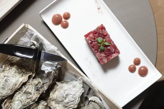 ostriche e tartare di pesce su piatto bianco